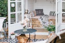 a lovely boho she shed with white planked walls, a crate daybed with pillows, a star garland, an additional outdoor space with furniture