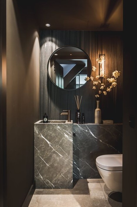 a luxurious contemporary powder room with a stone sink and vanity, a mirror and some stone on the wall plus blooms