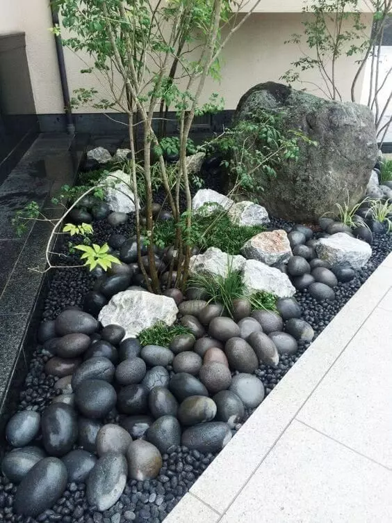 a mini front yard Japanese garden with large rocks and pebbles, some greenery and trees is a gorgeous idea for a contemporary home