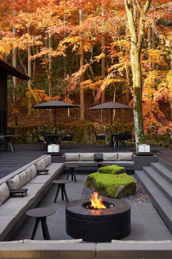 a minimalist sunken fire pit with a built-in upholstered bench, a fire pit and a piece of rock garden with moss