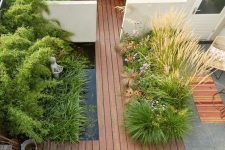 a minimalist townhouse garden with a wooden deck, a pond, planted herbs and grasses and a built-in bench