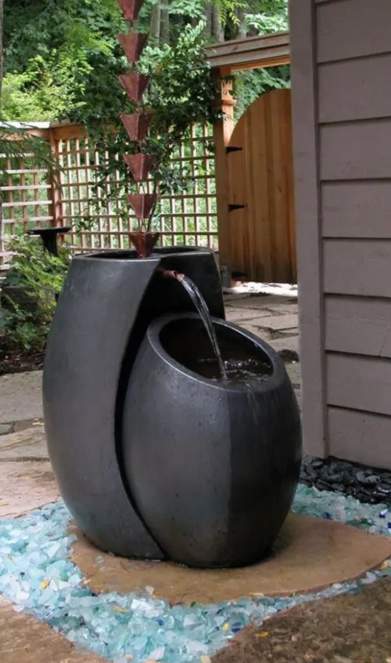 a minimalist zen fountain of two black vessels and wind chimes over it is a lovely idea for a minimalist space