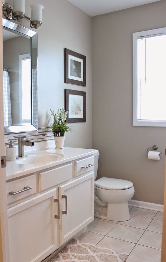 a modern bathroom with greige walls, a white vanity, white appliances, a mini gallery wall, a large mirror