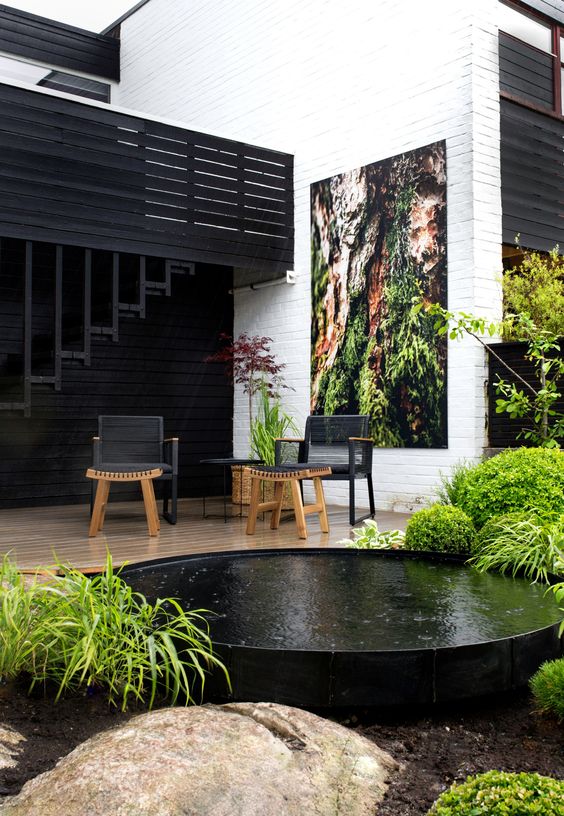 a modern black and white outdoor space refreshed with greenery and a black stock tank pool for a quick dip