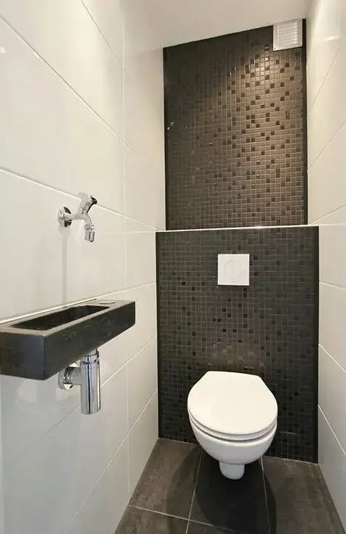 a modern black and white powder room with large scale white and small scale black tiles, a floating toilet and a black stone sink