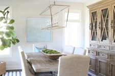 a modern coastal farmhouse dining room with a stained buffet, a stained table, upholstered chairs, a modern chandelier