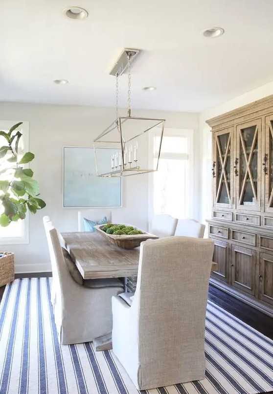 a modern coastal farmhouse dining room with a stained buffet, a stained table, upholstered chairs, a modern chandelier
