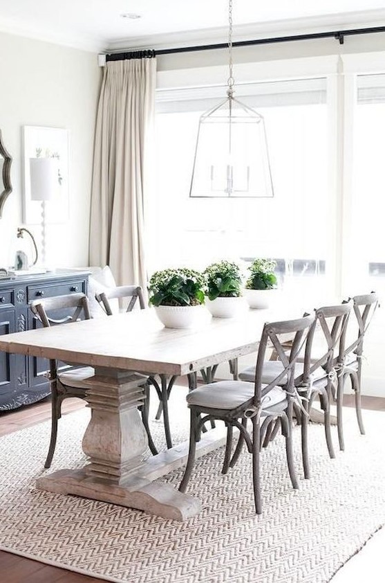 a modern farmhouse dining room with a whitewashed table, white chairs, a frame lamp and a buffet