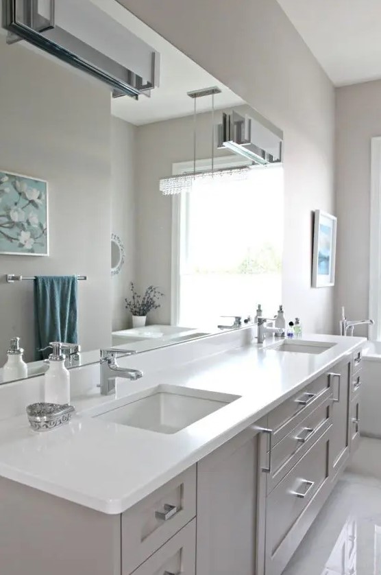 a modern farmhouse greige bathroom with a matching vanity with a white stone countertop, white appliances and neutral fixtures plus wall lamps
