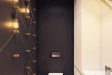 a modern powder room with industrial touches – bulbs on the wall, black tiles and a white storage unit