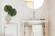 a modern to boho powder room with printed wallpaper, a sink on a stand, a round mirror and a catchy vase with leaves