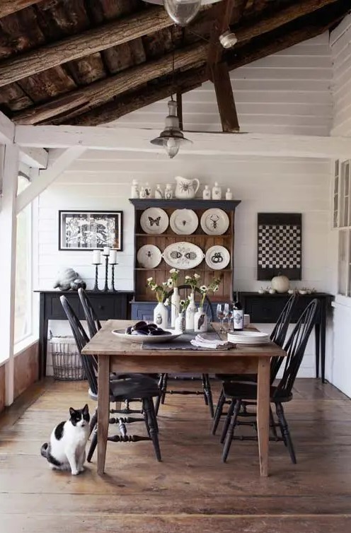 a monochromatic dining space with a black and stained wooden furniture, decorative plates and artworks