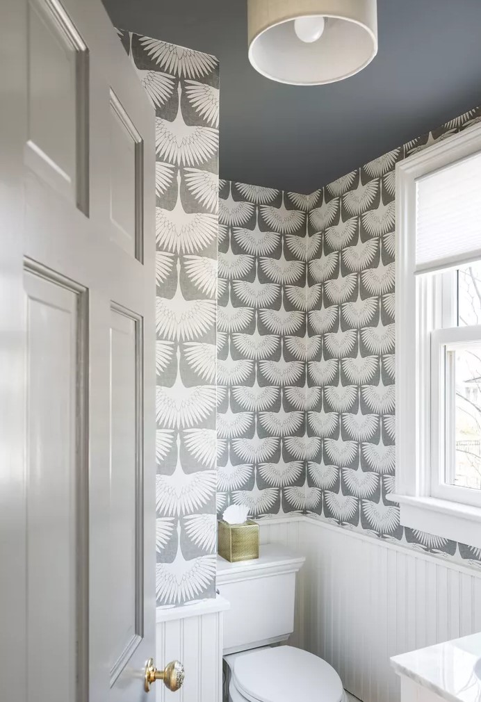 a monochromatic grey and white powder room with paneling, printed wallpaper, white appliances and a white vanity