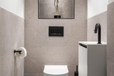 a neutral contemporary powder room clad with large scale greige tiles, with a floating vanity and black touches
