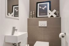 a neutral contemporary powder room done in taupe and white, an artwork, a wall-mounted sink and a large mirror