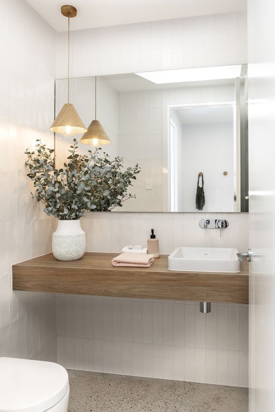 a neutral contemporary powder room with a light-stained built-in vanity, white appliances, a pendant lamp and a large mirror
