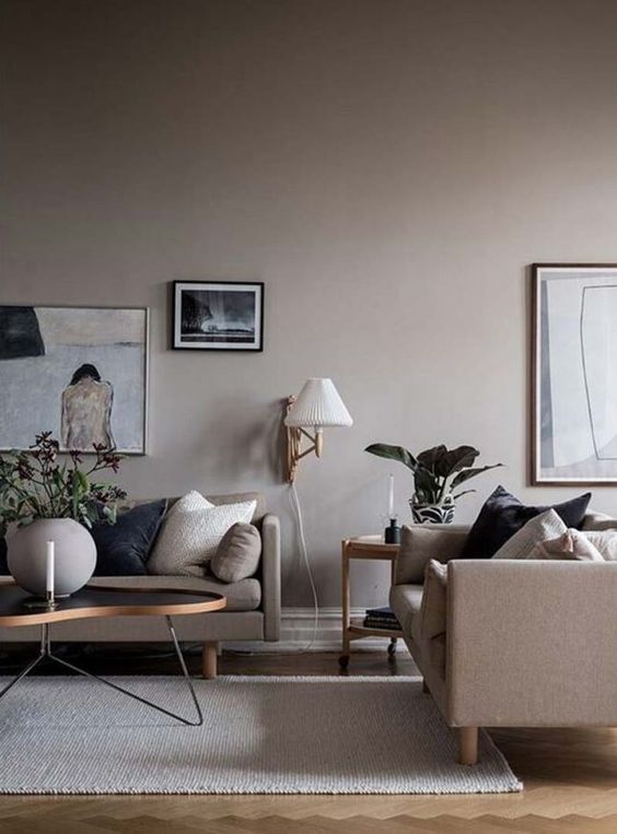 a peaceful greige living room with greige sofas, a coffee table, some greenery and a gallery wall with various art