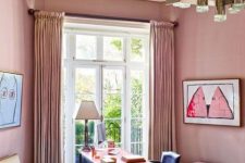a pink home office with pink curtains, a chic desk, a navy chair, a fuchsia bench, a creamy chair and a gold chandelier
