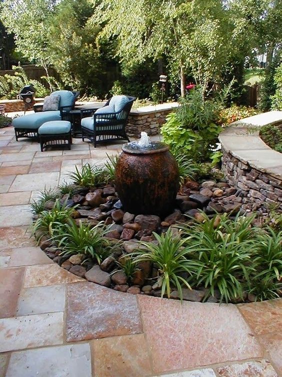 a pretty amphora fountain placed on large rocks and greenery will add curb appeal to any outdoor space