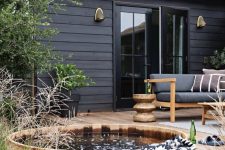 a pretty and welcoming wooden deck with a built-in tub, modern furniture and potted and just growing plants