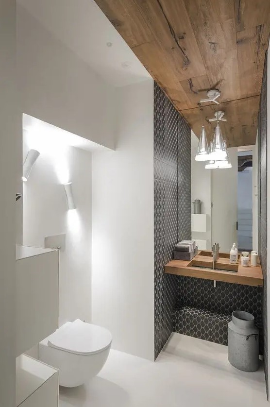a pretty contemporary powder room accented with printed tiles, a wooden ceiling and a floating sink, a mirror and sconces and a white toilet zone