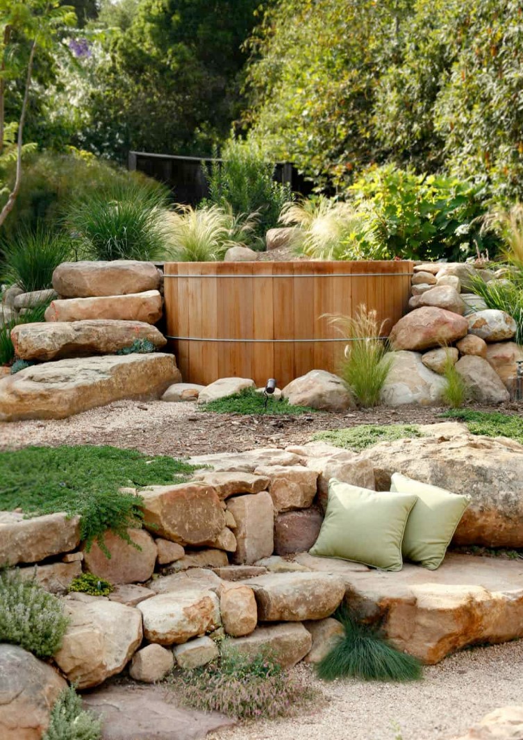 a pretty natural outdoor space with stone steps and some greenery plus a wood bathtub right in the garden to feel like in a natural spa