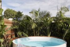 a raised round pool surrounded with tropical plants is a stylish and minimal option to go for