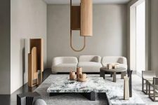 a refined greige living room with curved seating furniture, a white stone coffee table, a wooden pendant lamp and a matching decoration is chic