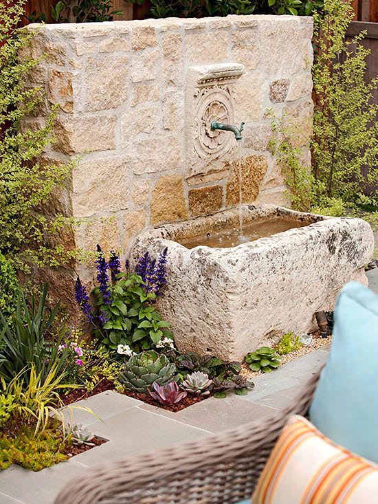 a refined vintage-inspired space with a stone fountain with a faucet, with some succulents and blooms around it