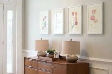 a retro entryway with delicate greige walls, a stained console table with storage and a mini gallery wall plus a crystal drop chandelier