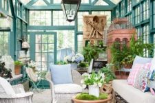 a she shed in vintage style of a former glasshouse, with white wicker furniture, tables, a sofa, potted plants and some vintage furniture