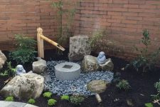 a small Japanese front yard with pebbles, greenery, a stone and bamboo fountain, rocks, shrubs is a lovely space