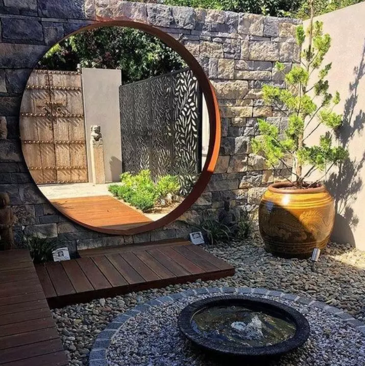 a small Japanese garden at the entrance, with a potted tree, greenery, pebbles and a small modern fountain is a gorgeous idea