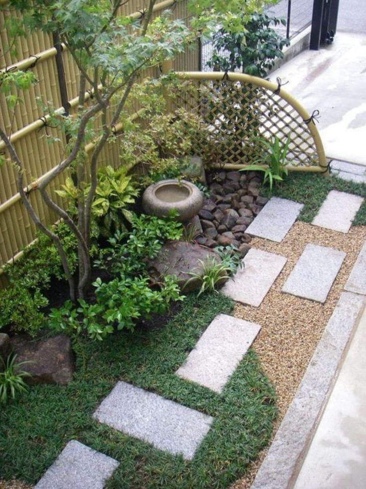 a small Japanese garden with lawn, greenery, a small tree, a bowl with water, rocks and a bamboo fence is a cool decor solution