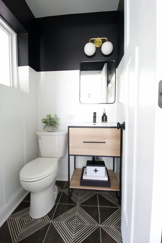 a small and chic modern powder room with black walls and white paneling, a black and white floor, a timber vanity and white appliances