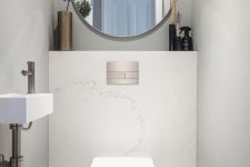 a small contemporary powder room with stone tiles, a round mirror and white appliances plus some decor