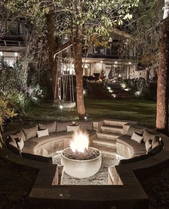a small sunken patio with a fire pit and built-in round benches with pillows is a lovely space to relax in the evening