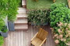 a small townhouse garden with a wooden deck, a lawn, some potted greenery and wooden furniture