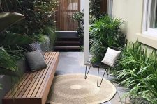a small townhouse garden with stone tiles, a built-in bench, hairpin leg furniture and potted greenery with much texture
