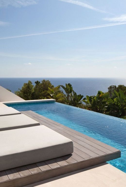 a small yet chic infinity pool with a wooden deck and minimalist loungers plus a fantastic sea view is amazing