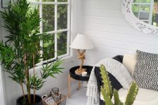 a small yet elegant she shed living room with a black wicker table and sofa, a side table, some rugs and potted greeneyr