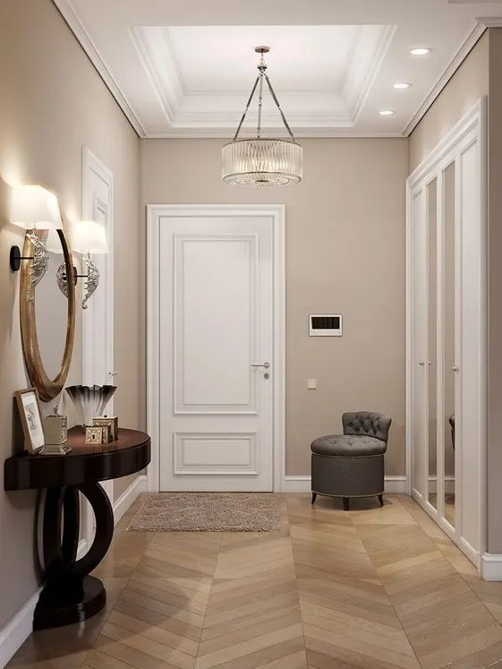 a sophisticated greige entryway with white doors and a built in storage unit with mirror doors, a grey stool and a refined dark console table plus cool lamps