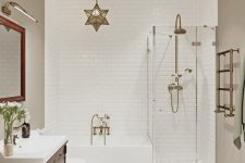 a stylish bathroom with greige walls, a mahogany vanity, a bathtub and a glass enclosed shower, brass fixtures