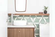 a stylish modern powder room with green printed tiles, a floating vanity, white appliances and a catchily-shaped mirror