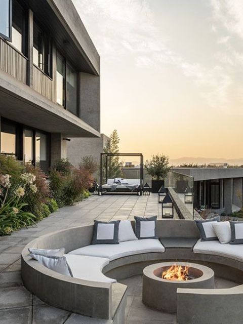 a sunken concrete minimalist patio with a fire pit and lots of pillows is amazing for spending time and to relax in