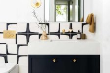 a super chic modern powder room in black and white, with a black vanity and a neutral sink, gold touches and a curved mirror for more chic