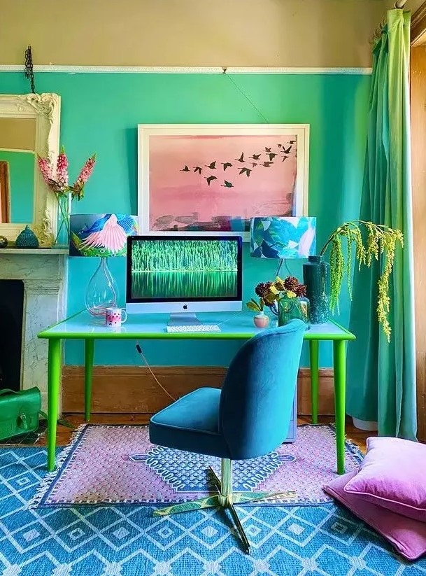 a vibrant maximalist home office with bold ombre walls, a blue and yellow desk, a bold blue chair, colorful almps, rugs and pillows