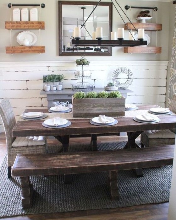 a vintage farmhouse dining area with a whitewashed wall, shelves, dark stained wooden dining set and a wooden chandelier