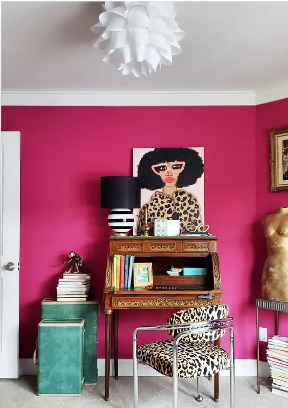 a whimsical magenta home office with a vintage wooden desk bureau, a leopard print chair, green storage units and bold art