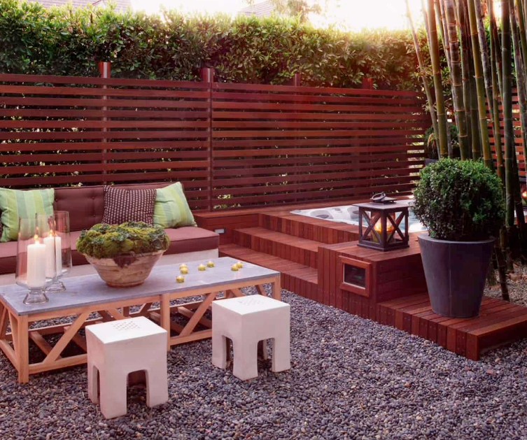 an above ground hot tub with wood surround and steps in a cozy backyard with modern outdoor furniture, potted plants and bamboo